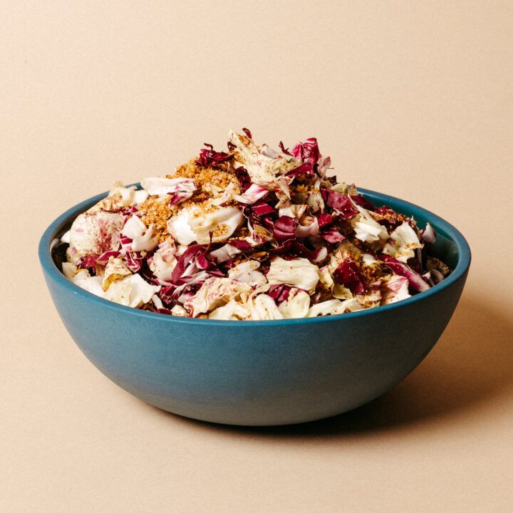 A radicchio salad in a blue bowl on a neutral backdrop.